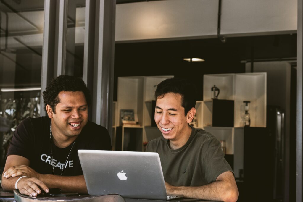 Employee Well-Being: two smiling men looking at MacBook