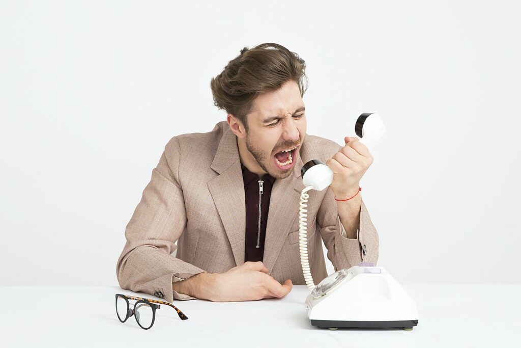 man holding telephone screaming over a communication barrier